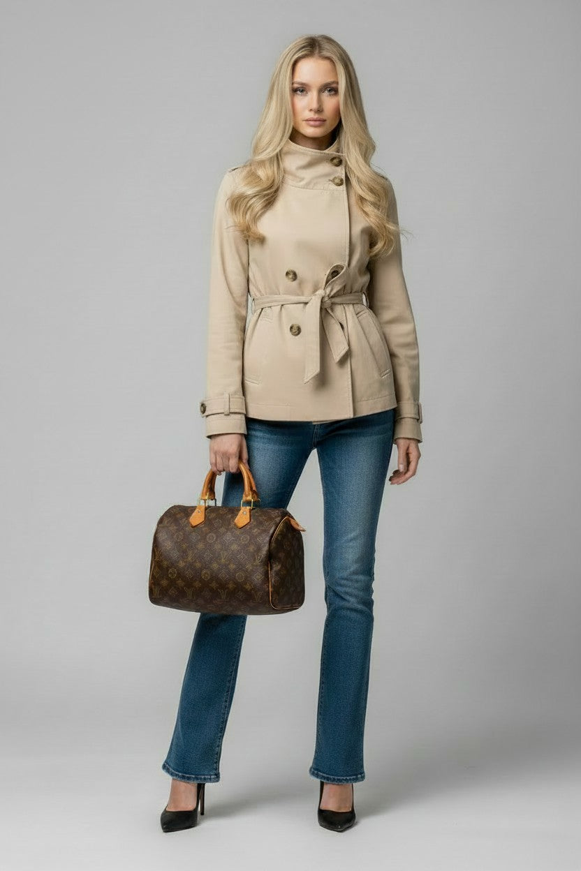 Model wearing a beige trench coat carrying a Louis Vuitton Speedy handbag
